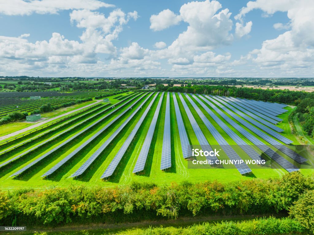 Aerial view of solar panels on green field at suburb in sunny day