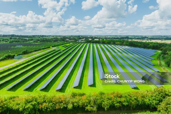 Aerial view of solar panels on green field at suburb in sunny day